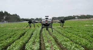 Agricultural spraying drone flying over rows of leafy crops